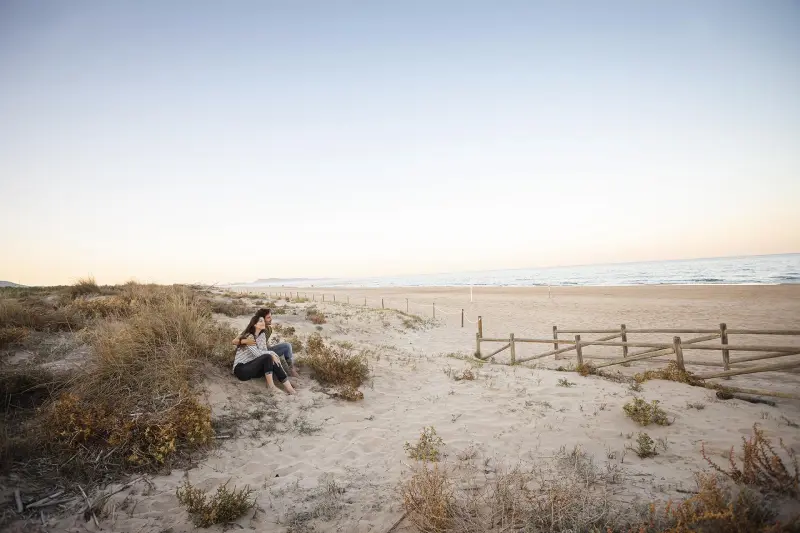 Escapada romántica en Gandía Pareja disfrutando de la Playa de l'Ahuir al atardecer